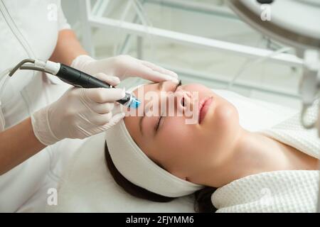 Eine Frau erhält Laserbehandlung des Gesichts in einer Kosmetikklinik wird ein Konzept der Hautverjüngung entwickelt. Laserpeeling Stockfoto