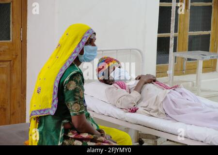 Ältere indische Frau in einer medizinischen Maske, die neben ihr sitzt Ehemann in einem Krankenhaus Stockfoto