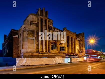 Harrow Street bei Nacht mit Art déco-Safari-Kinogebäude vor der Renovierung und Londons rotem Bus in Bewegung, Harrow, England, Stockfoto