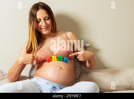 Frau zeigt auf Mädchen Wort aus Buchstaben auf Bauch gemacht Stockfoto