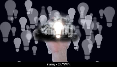 Zusammensetzung der beleuchteten Glühbirne mit Wolke über der Hand und Mehrere Glühlampen auf schwarzem Hintergrund Stockfoto