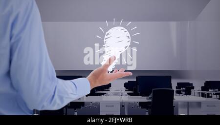 Die Komposition der Ikone der beleuchteten Glühbirne über der Hand des Geschäftsmannes Leeres Büro Stockfoto