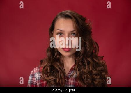 Nahaufnahme charmante selbstbewusste Frau schaut auf die Kamera auf rotem Hintergrund, Copy Space Stockfoto