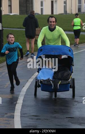 Troon 5k Park Run Along Troon Seafront, Ayrshire, Scotland, UK Vater Simon Woodliff mit dem 9-jährigen Sohn Finley, während Carrick (1) und Angus (5) im Kinderwagen mitgeschoben werden Stockfoto