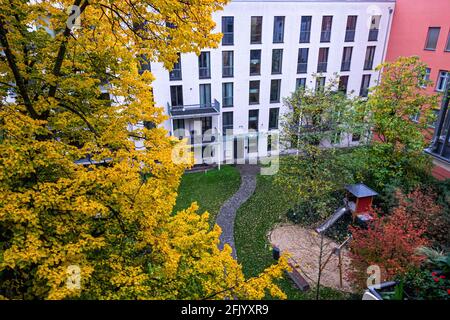 Innenhof Garten des Mehrfamilienhauses mit Spielplatz im Herbst. Brunnenstraße, Mitte, Berlin, Deutschland. Bunte Laub auf Bäumen Stockfoto
