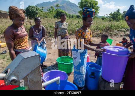Mzuzu, Malawi. 30-05-2018. Mutter und Kinder aus der Gemeinde kommen in Malawi zusammen, um trinkbares Wasser zum Trinken und Kochen zu holen. Stockfoto