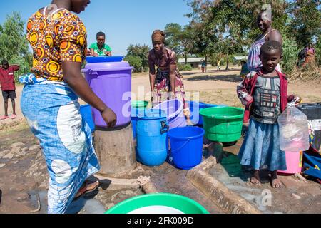 Mzuzu, Malawi. 30-05-2018. Mutter und Kinder aus der Gemeinde kommen in Malawi zusammen, um trinkbares Wasser zum Trinken und Kochen zu holen. Stockfoto