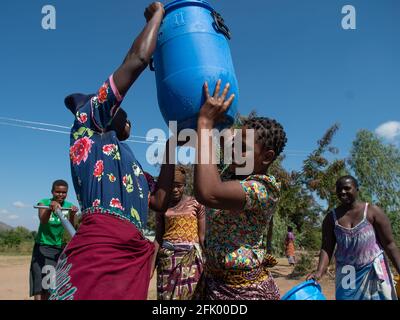 Mzuzu, Malawi. 30-05-2018. Mutter und Kinder aus der Gemeinde kommen in Malawi zusammen, um trinkbares Wasser zum Trinken und Kochen zu holen. Stockfoto