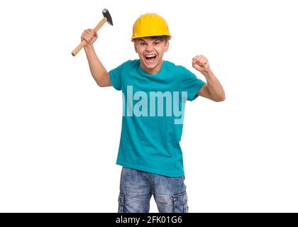Porträt eines Jungen mit Hammer, in gelbem Hut, isoliert auf weißem Hintergrund. Netter junger Teenager mit Werkzeugen, sieht verwirrt aus Stockfoto