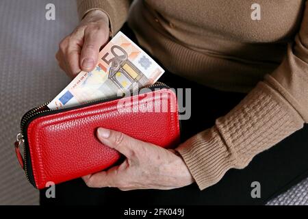 Eine ältere Frau nimmt einen Euro-Schein aus ihrem Portemonnaie. Konzept der Rentenzahlungen, Ersparnisse im Ruhestand, Rentner mit Geld Stockfoto