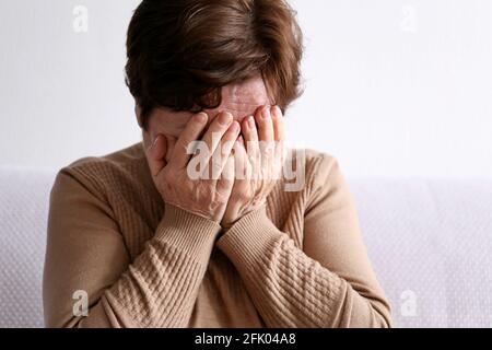 Ältere Frau bedeckt ihr Gesicht mit Händen. Weinende Person, verärgert und Traurigkeit Konzept Stockfoto