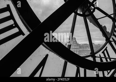 PARIS, FRANKREICH - 6. APRIL 2014: Eine Uhr mit römischen Ziffern im Museum D'Orsay und der Blick auf den Louvre. Musee d'Orsay hat den größten Koll Stockfoto