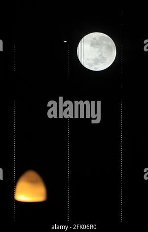 San Francisco, USA. April 2021. Der Supermond ist zwischen den verdrehten Seilen der Bay Bridge und dem Licht am Ufer in San Francisco, USA, am 26. April 2021 zu sehen. Quelle: Liu Yilin/Xinhua/Alamy Live News Stockfoto