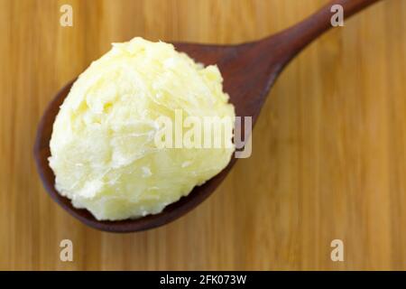 Kaltgepresstes, nicht raffiniertes Sheabutter-Fett, das aus Nusskernen gewonnen wird Von afrikanischem Sheabaum in Holzlöffel (Vitellaria paradoxa) Stockfoto