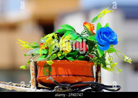 Bunte künstliche Blumenstrauß mit Fuchsia-blauer Rose und ecuadorianischen gelben Sonnenblumen und grünen Blättern im Tontopf. Stockfoto