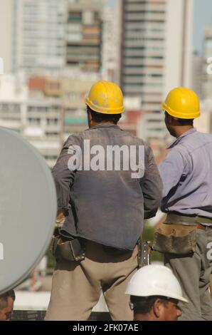 Zwei Bauarbeiter planen ihren Arbeitstag mit Arbeitskleidung und arbeiten am Bau eines hohen Gebäudes Stockfoto