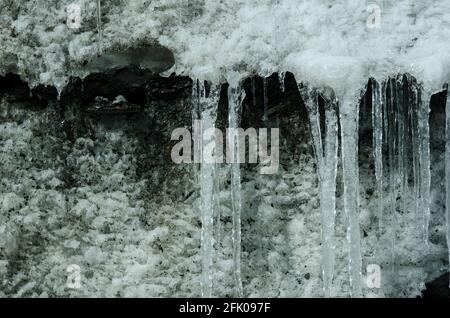 Eiszapfen bilden sich dort, wo geschmolzener Schnee und Eis vom Rand des Xinjiang Tianshan No 1 Glaciers tropft, wo Eis und Schnee über viele Jahre auf die felsigen Hänge der Tianshan-Berge im östlichen Xinjiang, China, PRC, verdichtet wurden. © Time-Snaps Stockfoto