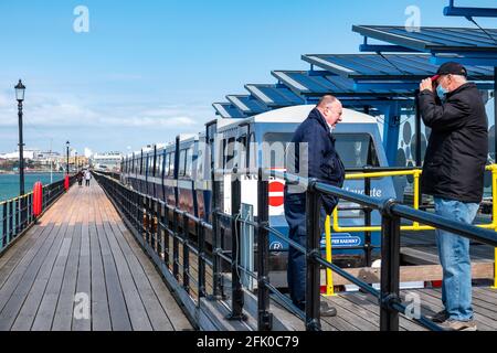 Southend am Sea Pier, essex, großbritannien im Frühjahr packten sich die Leute gegen die Kälte und sprachen am Ende der Eisenbahn mit einem Elektrozug Stockfoto