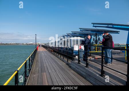 Southend am Sea Pier, essex, großbritannien im Frühjahr packten sich die Leute gegen die Kälte und sprachen am Ende der Eisenbahn mit einem Elektrozug Stockfoto