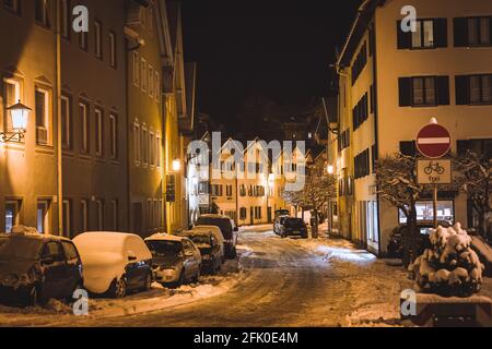 Verschneite Straße in Füssen, im Süden Deutschlands, beleuchtet von Glühlampen. Stockfoto