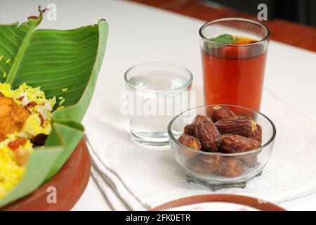 Getrocknete Datteln, ramadan getrocknete Datteln in eine Glasschale mit gestellt Ein Glas reines Trinkwasser und Limettentee Neben Huhn biryani auf einem weißen Text Stockfoto