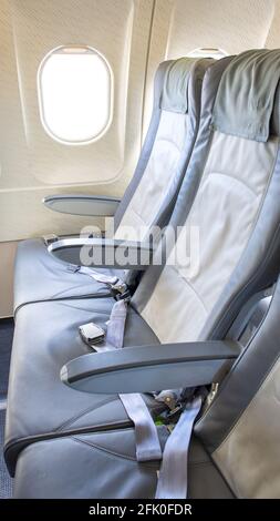 Leere Sitze eines modernen Flugzeugs, Fensterseite mit eingesendem Licht Stockfoto