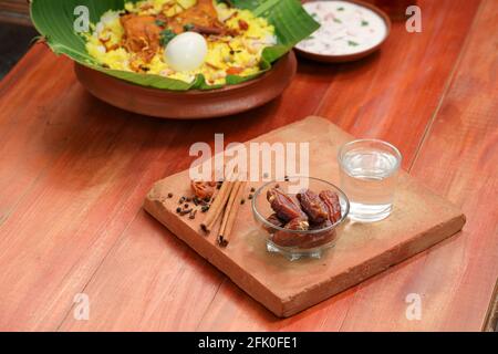 Getrocknete Datteln, ramadan getrocknete Datteln in eine Glasschale mit gestellt Ein Glas reines Trinkwasser auf ein Holz gelegt Textur mit Biryani und Beilage in Th Stockfoto
