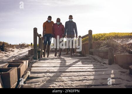 afroamerikanischer Vater und seine beiden Söhne tragen Gesichtsmasken Gemeinsam auf der Brücke spazieren Stockfoto