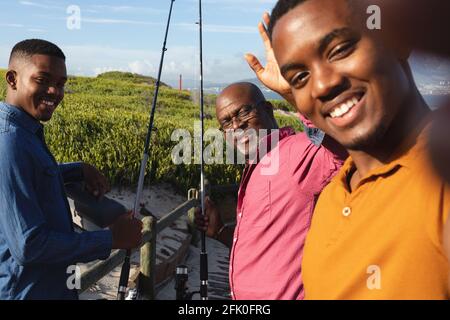 afroamerikanischer Vater und seine beiden Söhne lächeln zusammen Ein Selfie auf der Brücke machen Stockfoto