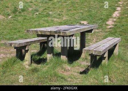 Gut gebrauchter, fester Holzpicknicktisch und zwei Holzbänke im Freizeitbereich Lane Ends, einem öffentlichen Bereich neben der Meeresmauer in Pilling, Lancashire. Stockfoto