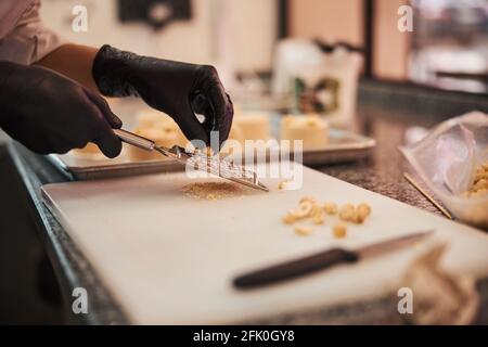 Qualifizierte Konditorei, die Haselnüsse auf einem Schneidbrett rost Stockfoto