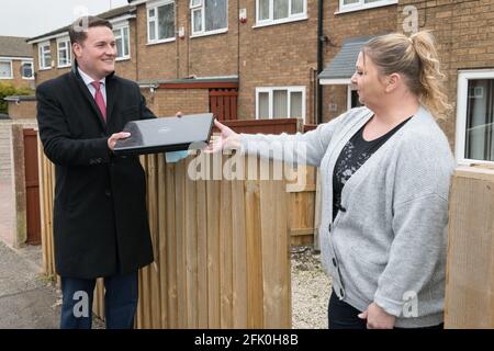 Mansfield Woodhouse, Nottinghamshire, England, Großbritannien. April 2021. Wes Streeting Labour Party M.P. für ilford North und Shadow Minister for Education (Schulen) (links) sprachen mit einer lokalen Mansfield Woodhouse Residenz Vicki Chapell (rechts) über die Spende eines Laptops und wie es ihrer Familie helfen soll, online auf ihre Schule zuzugreifen, um während der Sperre zu lernen. Quelle: Alan Beastall/Alamy Live News Stockfoto