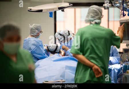 Essen, Deutschland. April 2021. Ein Team von Ärzten und chirurgischen Assistenten steht während einer Operation im HNO-Operationssaal der Universitätsklinik um einen Patienten herum. Der Neubau des Operationsflügels für den Augen- und HNO-Betrieb kostete fast 70 Millionen Euro. Dies sind laut Universitätsklinikum derzeit die modernsten Operationssäle in Deutschland und Europa. Quelle: Jonas Güttler/dpa/Alamy Live News Stockfoto