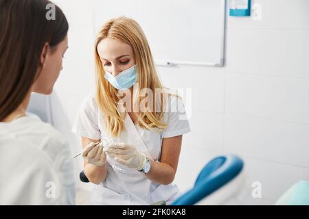Ärztin, die mit der Zahnsonde auf den Kieferguss zeigt Stockfoto