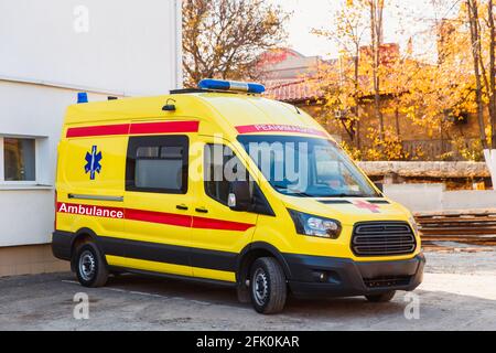 Zaporozhye, Ukraine- November 08 2019 :Gelber Krankenwagen steht in der Nähe des Krankenhausgebäudes. Seitenansicht. Stockfoto