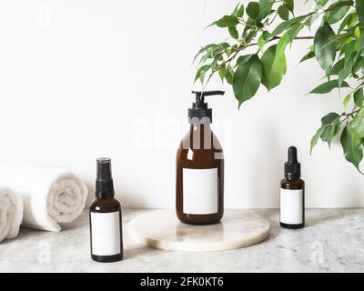 Modell aus braunen Glasflaschen für Kosmetikprodukte und Baumwollhandtücher im Badezimmer. Vorderansicht. Kopierraum. Kosmetikprodukte nachahmen. Blogging minimal Stockfoto