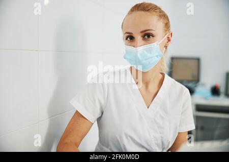 Zahnklinik Arbeiter beobachten Kamera, während in Maske sitzen Stockfoto