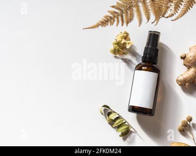 Bio-Naturprodukt - Öle, verschiedene Trockenpflanzen und Glasflasche Mockup auf weißem Hintergrund pflanzliche Alternativmedizin und Aromatherapie. Draufsicht. Stockfoto