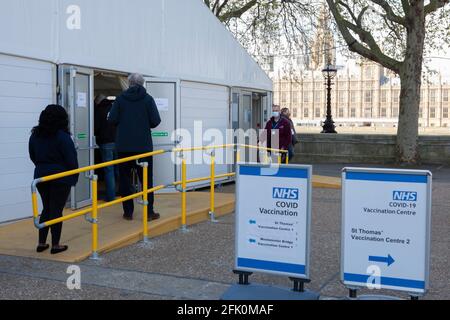 London, Großbritannien, 27. April 2021: Die Menschen stehen am Ende einer Impfstelle auf dem Gelände des St. Thomas's Hospital vor den Houses of Parliament am gegenüberliegenden Ufer der Themse. Premierminister Boris Johnson steht immer noch vor Vorwürfen, dass er es vorgezogen habe, „Körper häufen sich“ anstatt eine dritte Sperre zu haben. Anna Watson/Alamy Live News Stockfoto