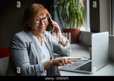 Fröhliche reife Frau genießt ihre Fernarbeit Stockfoto