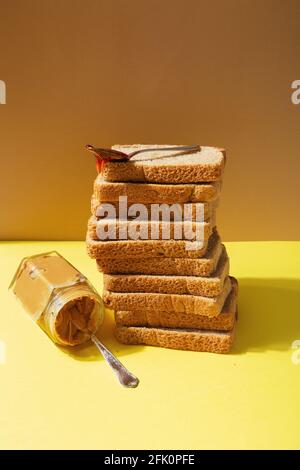 Zutaten für Erdnussbutter und Gelee-Sandwiches. Löffel mit Erdbeermarmelade auf Haufen Toastbrot Stockfoto