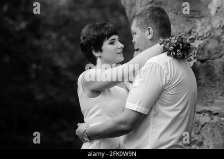 Brautpaar umarmen und küssen vor dem Hintergrund von Wasser und Ein Steinbogen Stockfoto