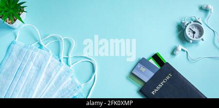 Reisepass und medizinische Maske auf blauem Hintergrund. Sicheres Reisekonzept während der Coronavirus-Pandemie. Flatlay, Kopierbereich. Stockfoto