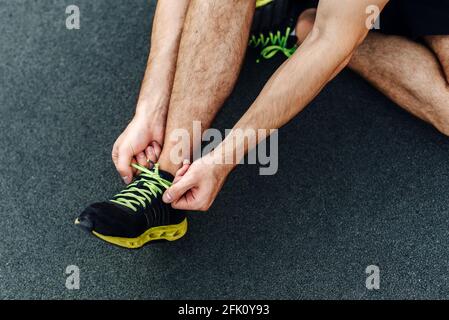Männliche Hände binden die Schnürsenkel der Turnschuhe vor dem Training im Freien. Nahaufnahme. Stockfoto