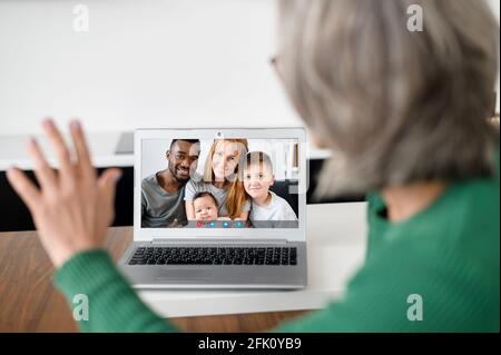 Ältere Großmutter mit Laptop für Online-Gespräche mit der Familie auf der Ferne. Ältere Frau, die die Computer-App für Videoanruf und virtuelle Treffen mit erwachsenen Kindern nutzt. Mitarbeiter im Ruhestand und Technologie Stockfoto