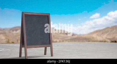 Menuboard, leer. Schwarze stehen draußen auf der Straße. Tafel mit Holzrahmen für Restaurantwerbung, Ankündigung. Blauer Himmel, Landschaft Stockfoto