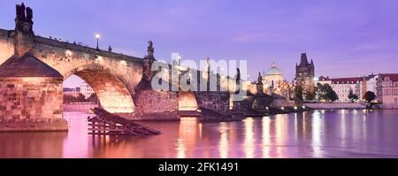 Banner, Karlsbrücke in Prag bei Sonnenuntergang. Panoramabild des Moldau-Flussufers in lila, rosa Dämmerung mit beleuchteter Karlsbrücke, mittelalterlich Stockfoto