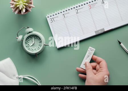 Wochenplaner, Schnelltest, schneller Corona-Test in deutscher Sprache. Flaches Lay mit Hand-haltendem Express-Antigen-Corona-Test. 2021 Kalender mit markiert Stockfoto