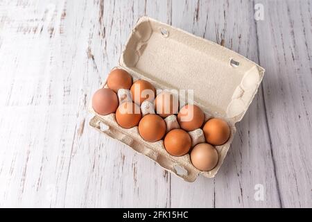 Hühnereier in einem gewellten Behälter zum Verpacken von Eiern auf hellem Holzgrund. Umweltfreundliche Verpackung. Speicherplatz kopieren Stockfoto