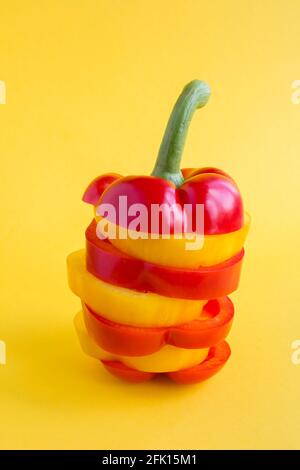 Pyramide mit gehackten roten und gelben Paprika auf dem gelben Hintergrund. Nahaufnahme. Position vertikal. Stockfoto